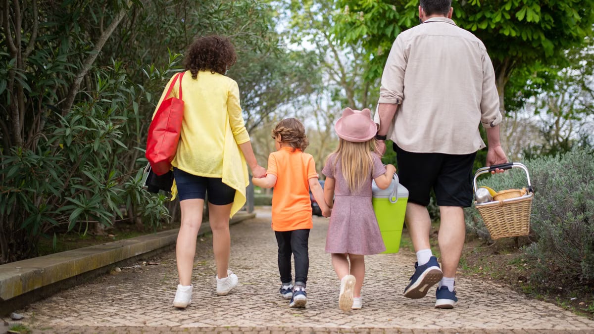 A family enjoying a walk in a picturesque Portuguese park carrying a picnic basket.